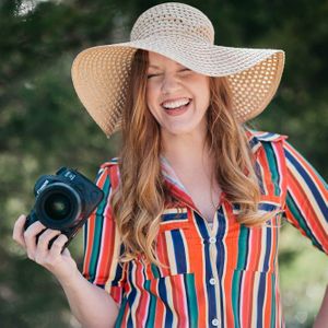 Female photographer, holding camera, floppy hat, stripe dress